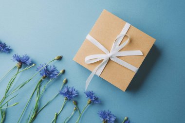 Mavi arka planda çiçek olan hediye kutusu
