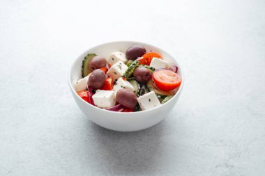 Beyaz kasede salatalık ve domatesli peynirli Yunan salatası.