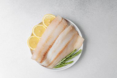 Beyaz arka planda limonlu ve biberiyeli ham pollock fileto.