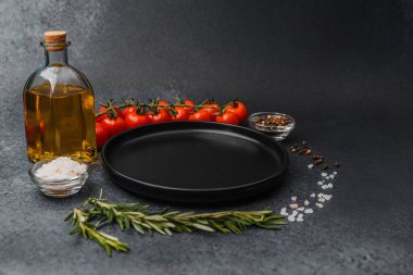 Siyah seramik tabak zeytinyağı kiraz domatesli biber biberli ve koyu sırt grubunda tuz.