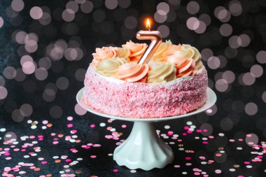Etrafında mum ve parıltı olan renkli bir doğum günü pastası neşe ve kutlama yaratır..