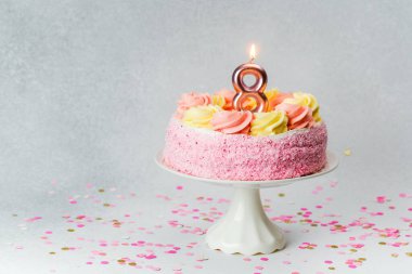 Güzel dekore edilmiş bir pasta pembe ve sarı renkli bir mum ile süslenir..