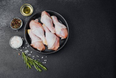 Siyah kasede çiğ tavuk budu ve baharat.