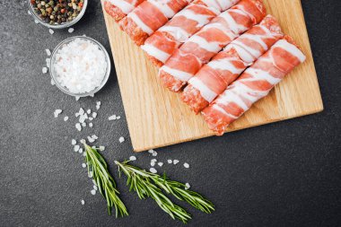 Pastırmaya sarılı çiğ et ruloları ahşap tahtaya baharatlı.