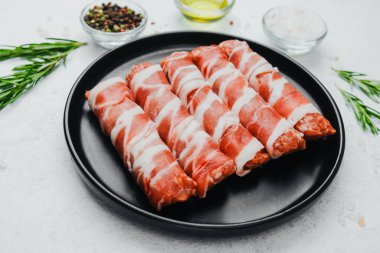 Domuz pastırması siyah tabakta baharat ve biberiye ile sarılmış.