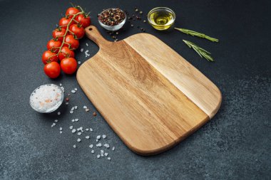 Kiraz domatesli tahta kesmek otlar, tuz ve baharatlar koyu arka planda.