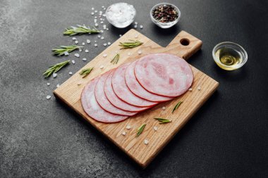 Siyah masa arkasında tuzlu ve biberiyeli dilimlenmiş domuz sosisi.