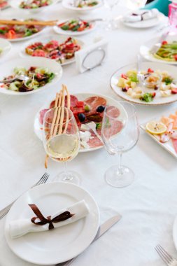 Çok güzel düzenlenmiş bir masada çeşitli gurme yemekleri ve şarap kadehleri sergilenir..
