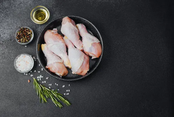 Siyah kasede çiğ tavuk budu ve baharat.