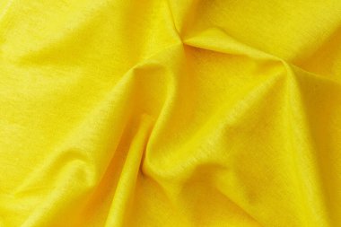 Yumuşak kırışıklıkları ve kıvrımları olan sarı kumaş arka planı kapat