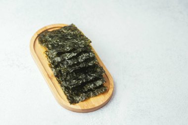 Ahşap tepside beyaz arka planda duran yosun parçaları.