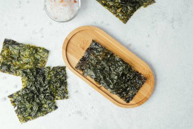 Beyaz arka planda bir kase tuzlu kavrulmuş yosun atıştırmalığı