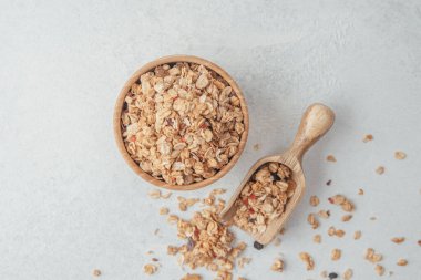Tahta kasede granola ve açık gri arka planda kepçe