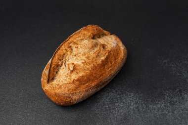Taze pişmiş tahıllı ekmek, koyu bir tezgahın üzerinde, kabuğunu sergiliyor..