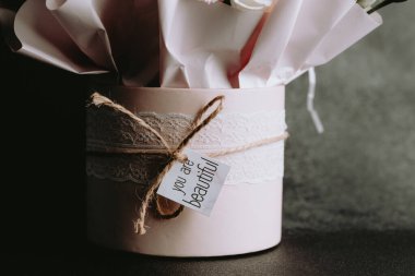 A pink gift box filled with flowers and decorated with a beautiful tag.