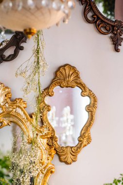 Süslü çerçeveli klasik aynalar güzel dekore edilmiş bir yerde ışığı yansıtır..