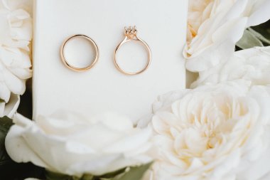 Beyaz güllerle çevrili alyanslar.