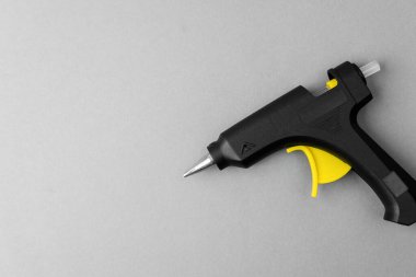 Gri zemin üzerinde sarı tetik olan sıcak tutkal tabancası.