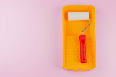 Ev boyama ve yenileme konsepti için pembe arka planda sarı tepside kırmızı saplı silindir.