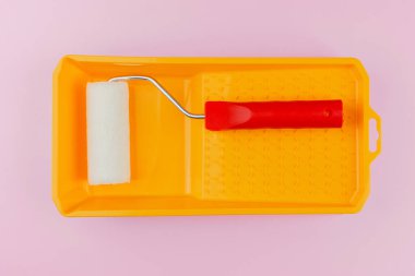 Ev boyama ve yenileme konsepti için pembe arka planda sarı tepside kırmızı saplı silindir.