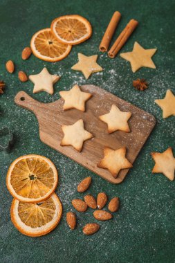 Noel yıldızı kurabiye hamuru ve portakallar şenlikli pişirme ve mevsimlik konsept için yeşil arka planda