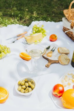 Meyveler, zeytinler ve peynirler beyaz piknik battaniyesinde. Temiz yeme, sadelik ve sağlıklı yaşam tarzları için kap kacak.