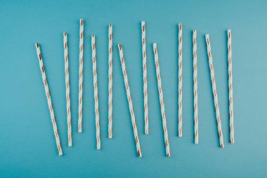 Doğum günü partisi ya da etkinlik konsepti için mavi arkaplanda altın çizgili kağıt pipetler