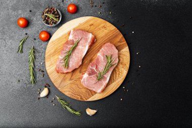 Biberiyeli, domatesli ve ahşap bir tahtaya dizilmiş iki parça et ve baharat..