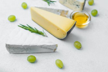 Tarafsız bir yüzeye yerleştirilmiş üzüm ve bal içeren çeşitli peynirler..