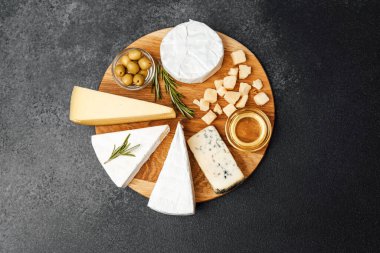 Peynir, zeytin ve bal seçimi ahşap bir tahtada güzelce düzenlenmiştir..