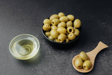 Koyu arkaplanda yeşil zeytin ve zeytin yağı