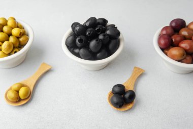 Kase içinde yeşil, siyah ve kalamata zeytinler ve ahşap kaşıklar.