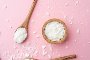 Ahşap kaşık soya gevreği ve kase pembe arka planda dağınık gevrek.