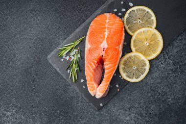 Limon dilimleri ve tahtada taze otlarla sunulan lezzetli somon bifteği..