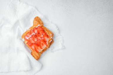 Taze çilekli pasta, beyaz bir kumaşın üzerinde özenle duruyor. Tatlılığını vurguluyor..