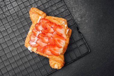 Üzerine taze çilek ve kremalı çiseleme serpiştirilmiş yumuşak hamur işi.