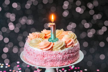 Renkli arkaplanda yanan bir mumla süslenmiş güzel bir pasta.
