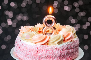 Güzel dekore edilmiş, pembe kremalı bir pasta ve sekiz numaralı mum..