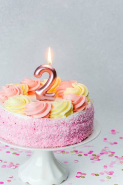 Pembe bir pasta, iki numara şeklinde bir mum içerir. Doğum günü için mükemmeldir..