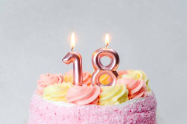 Pembe ve sarı kremalarla süslenmiş renkli bir pasta. 18 yıl boyunca mumlarla süslenmiş..