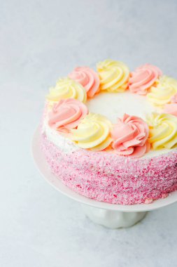 Çok güzel hazırlanmış bir pasta üzerinde pembe ve sarı kıvrımlı şekerlemeler var..