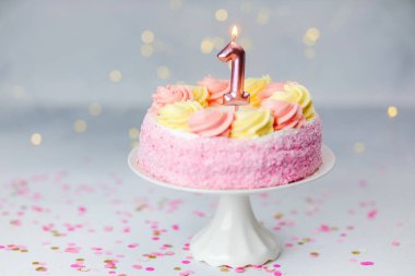 Bir numaralı mumla pembe ve sarı şekerli güzel dekore edilmiş bir pasta..