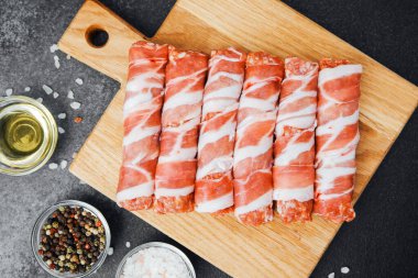 Pastırmaya sarılı çiğ et ruloları ahşap tahtaya baharatlı.