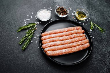 Siyah tabakta çiğ domuz sosisi ve biberiye.