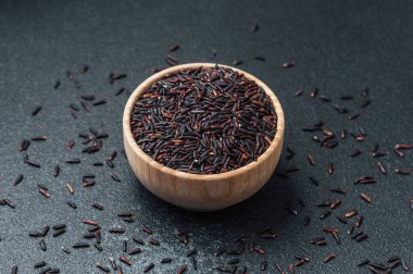 Tahta kasede saçılmış tanelerle çevrili siyah pirinç.