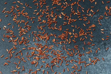 Koyu arkaplanda dağınık kırmızı pirinç taneleri, üst görünüm