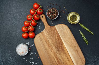 Kiraz domatesli tahta kesmek otlar, tuz ve baharatlar koyu arka planda.