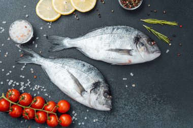 Limon biberli çiğ dorado balığı ve siyah arka planda biberiye.