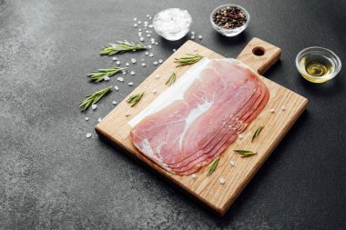 Tahtada deniz tuzu ve biberiyeyle jambon dilimleri var.