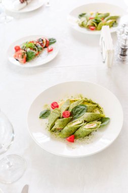 Renkli ıspanak ambalajları ve süsleri şık bir yemek ortamında sunuluyor..